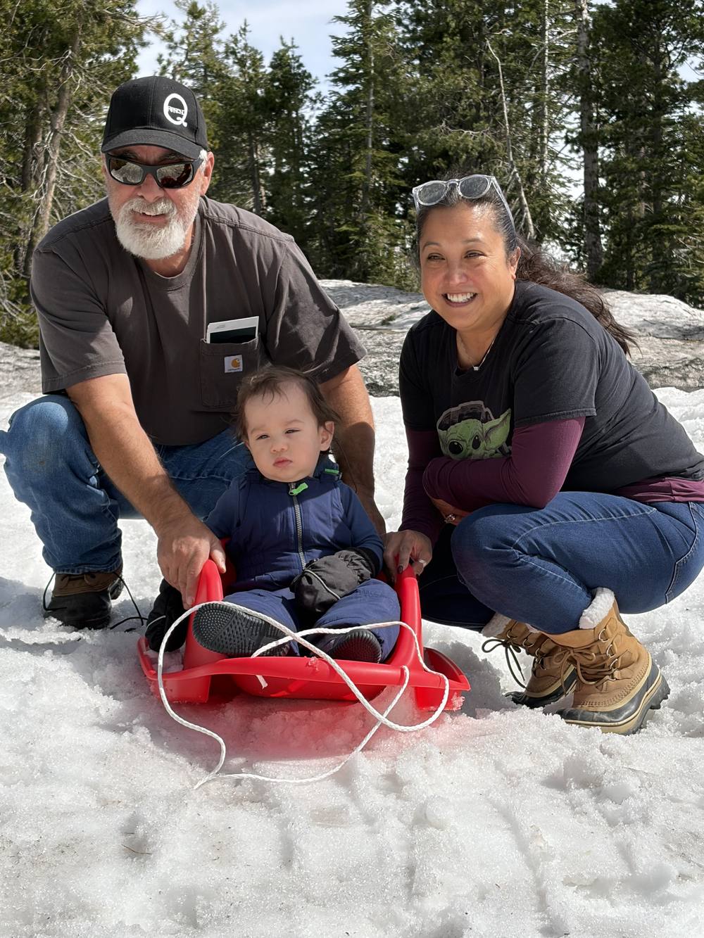 Marty, Roianne, and Theodore in the snow with a red sled